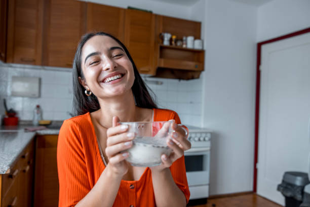 istock Young Woman Eating Cereal At The Kitchen Table 1413222905