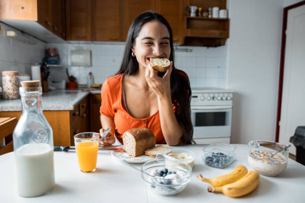 istock Woman Eating Bread In The Kitchen 1413222950