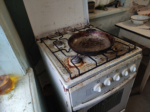 Very dirty and old gas stove and frying pan on a kitchen