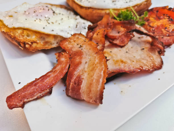 istock Big English breakfast with sunny fried eggs, bacon, tomatoes, ham on Turkish flat grilled bread on white dish 1413226780