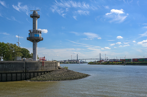 Radar tower with water level indicator at the Steinwerder coal ship harbor in the cargo port of Hamburg, Koehlbrand Bridge over the river Elbe in the background, blue sky, copy space, selected focus, narrow depth of field