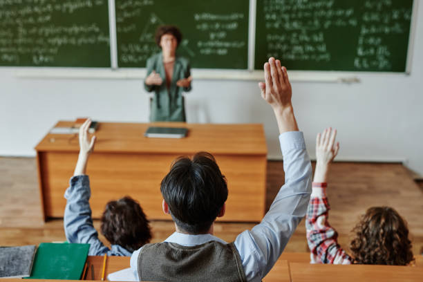 istock Rear view of several youthful students keeping their hands raised at lesson 1413233029