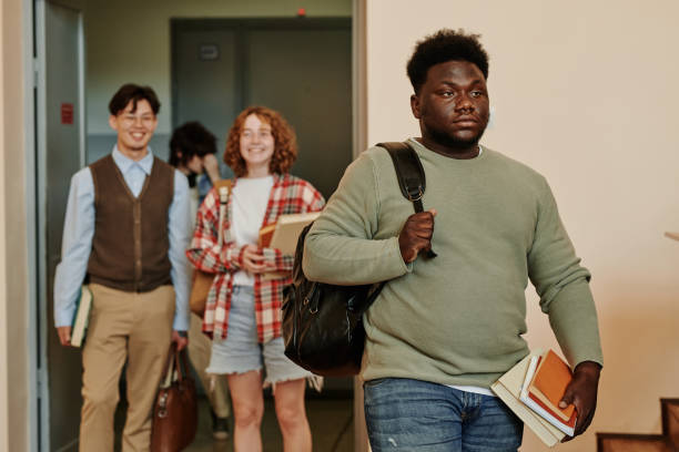 istock Youthful African American student in grey casual pullover entering lecture hall 1413233280