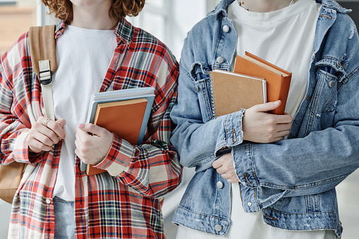Close-up of two friendly teenage girls in casualwear holding books