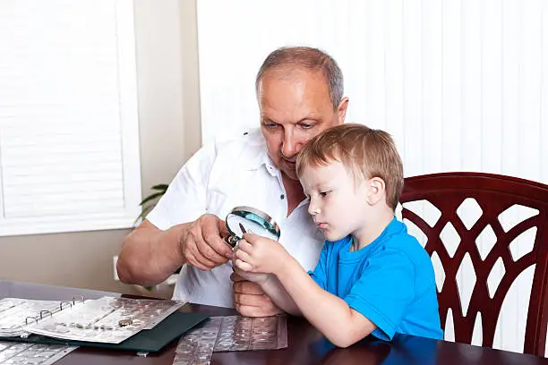 Photo of Grandfather and grandson looking at coin collection.