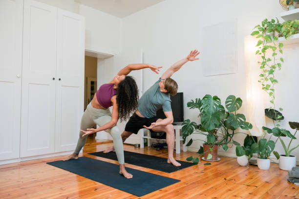 pareja de fitness practicando yoga de estiramiento en casa - stretching boyfriend indoors lifestyles fotografías e imágenes de stock