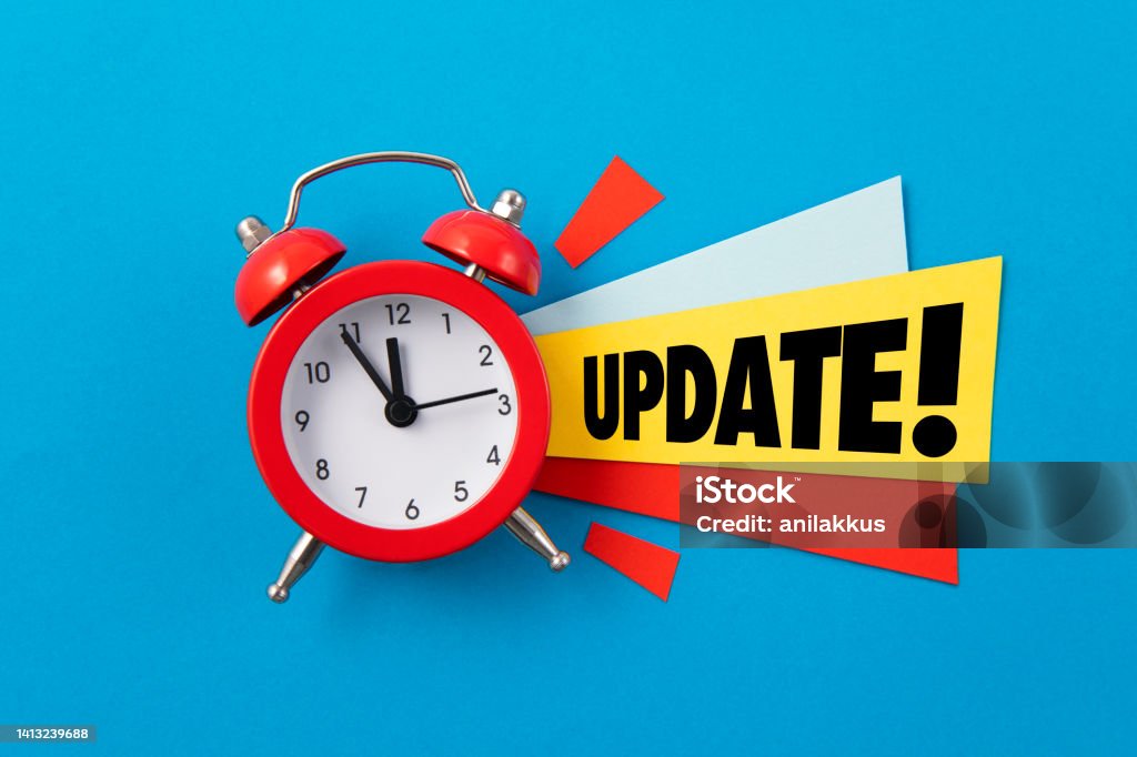 Update Red alarm clock with colored papers and update text on blue background Update - Communication Stock Photo