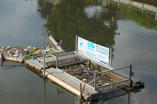 Waste collecting barrier in canal in Bangkok for reducing water pollution. Part of cleaner canals initiative by several national and international foundations amd companies like Coca Cola and Pepsi Cola as main brands. Scene is in canal in Ladprao near Wanghin Road