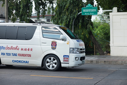 Thai ambulance on motion in Bangkok. Van is driving in street in Bangkok Ladprao. Text on car is connecting ambulance to hospital in Chokchai 4