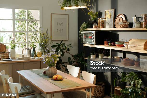 Interior Of Cozy Kitchen With Table And Chairs In The Center Against Window Stock Photo - Download Image Now