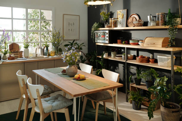 Part of spacious cozy kitchen with table, kitchenware and house plants