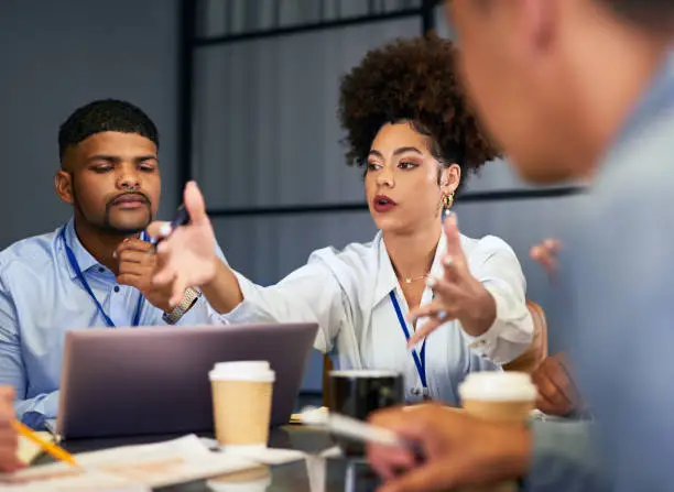 Photo of Talking, planning or meeting group of colleagues brainstorming ideas, discussing strategy on technology and paperwork. Businesswoman explaining to diverse creative marketing team in office boardroom