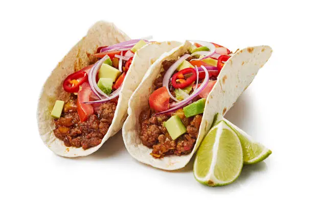 Photo of Two tacos with ground beef and lime on white background