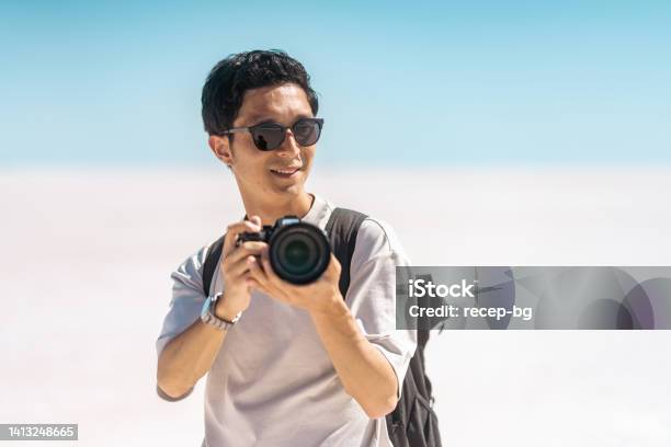 ソルトレークの白い塩でカメラでビデオや写真を撮る若い男性観光客