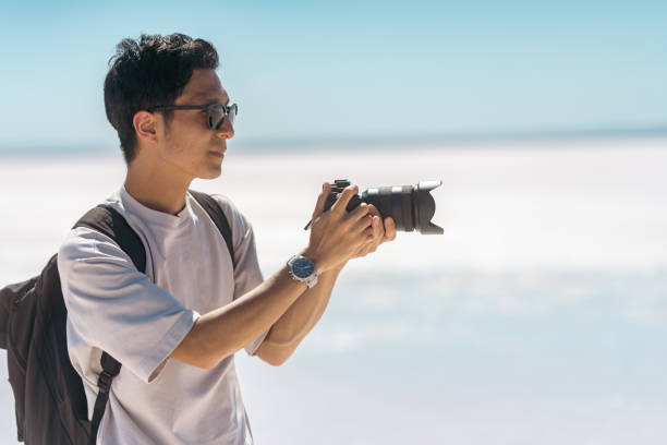 ソルトレークの白い塩でカメラでビデオや写真を撮る若�い男性観光客 - clear sky landmarks landscapes travel locations ストックフォトと画像