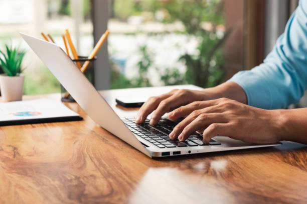 istock young man using laptop computer and mobile phone When looking for financial information in business, work at the desk. Writing with a pen, studying remotely from home and working from home. 1413249606