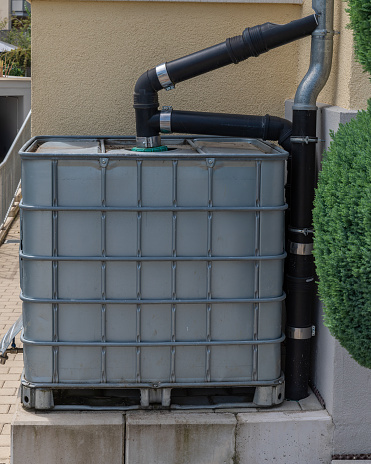 Modern rainwater cistern at the side of a house collecting water for environmental conservation. Conserving water reduces wear and tear on major resources such as water and wastewater treatment plants