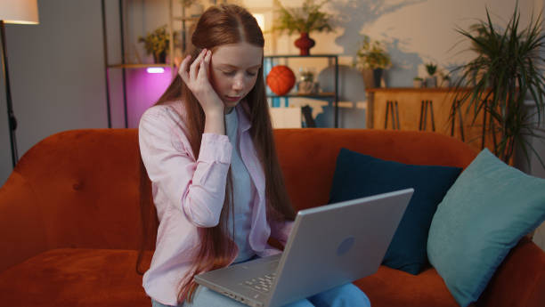 疲れた子供の女の子フリーランサーは、頭痛の問題の緊張と片頭痛、ストレスに苦しんでいるラップトップを使用しています - teenager problems typing teenagers only ストックフォトと画像