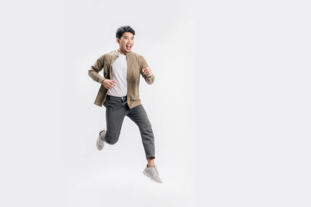 Full length handsome Asian man excited smile he is run in air on isolated white background. stock photo