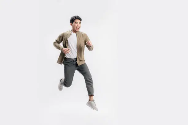 Photo of Full length handsome Asian man excited smile he is run in air on isolated white background.