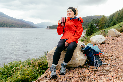 Woman taking a break while hiking along Loch Ericht to Culra Bothy in the Highlands of Scotland.