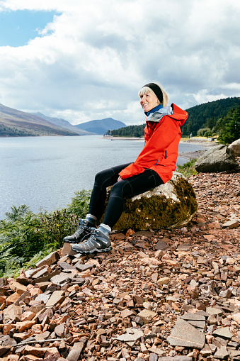 Woman taking a break while hiking along Loch Ericht to Culra Bothy in the Highlands of Scotland.