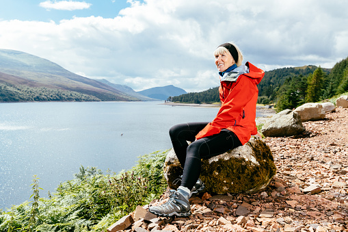 Woman taking a break while hiking along Loch Ericht to Culra Bothy in the Highlands of Scotland.