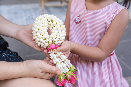 Small girl gives her mother jasmine garland on Thai Mother day.