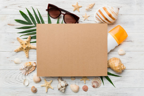 istock Summer time concept with blank greeting card and blank craft paper on colored background. Seashells from ocean shore in the shape of frame separated with space for text top view 1413268623