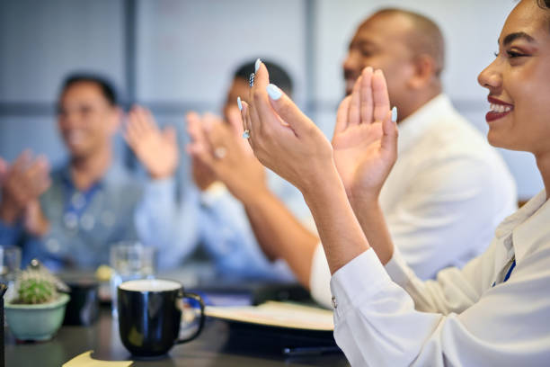 businesspeople sitting, smiling and clapping hands at work training meeting. multiracial business audience excited and positive at a corporate seminar. showing and celebrating company success - training business seminar clapping imagens e fotografias de stock