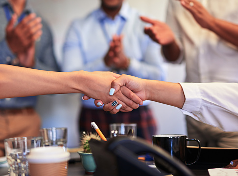 A handshake showing teamwork, collaboration and togetherness by colleagues in partnership after a group meeting in the office.  A successful agreement has been reached by coworkers in a business deal