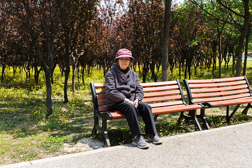 An old Chinese man is resting on a park bench