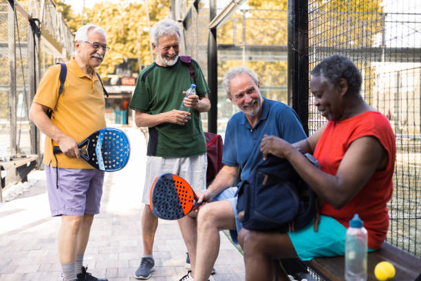 glückliche ältere freunde, die sich treffen, um pickleball zu spielen - tennis active seniors healthy lifestyle senior men stock-fotos und bilder