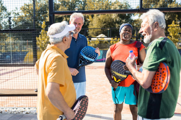 czwórka starszych przyjaciół bawiących się razem podczas gry w pickleball - mixed doubles zdjęcia i obrazy z banku zdjęć