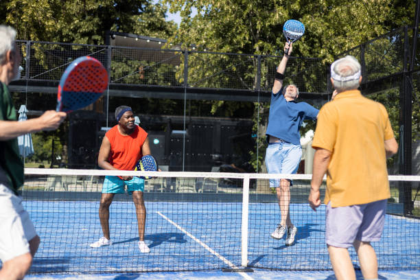 Group of four senior friends playing padel stock photo