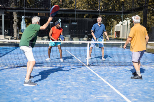 grupa czterech seniorów grających w pickleball - mixed doubles zdjęcia i obrazy z banku zdjęć