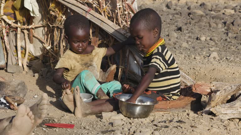 Close-up.Malnourished children due to extreme poverty, drought and climate change. Eating maize porridge infront of their dwelling.Kenya