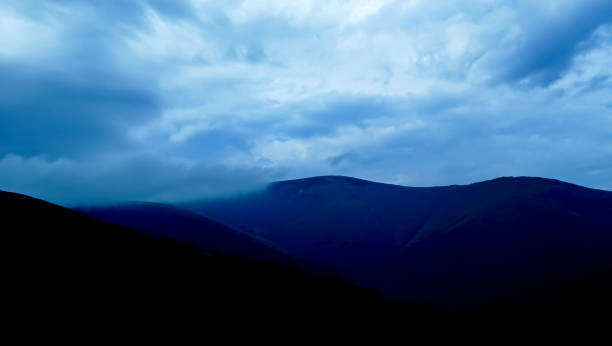 cielo drammatico nei toni blu-grigio sulle montagne. montagne quasi nere e cieli blu-grigi e nuvolosi. cieli tempestosi sulle montagne. - meteorology rain fog forest foto e immagini stock