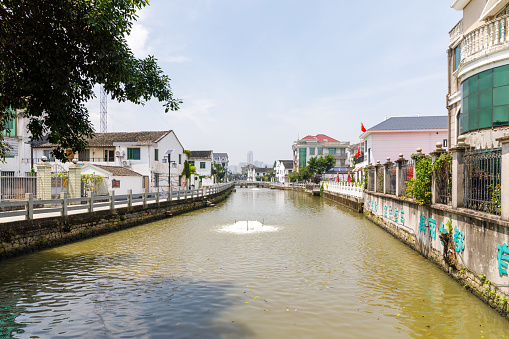 Wenzhou, China - June 23, 2022: A water canal flows in between buildings of a residential district. No people in the scene.