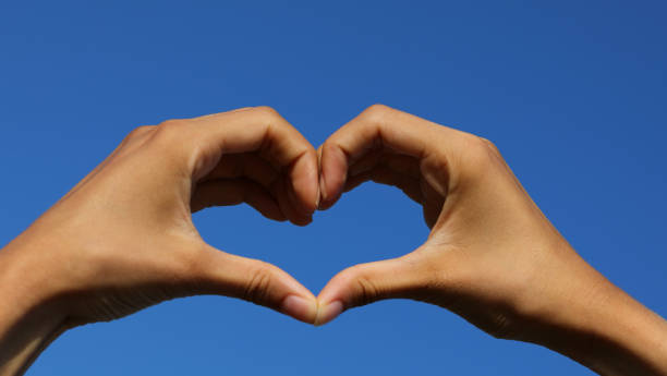 istock joined hands forming a heart on the blue sky in the background 1413281280