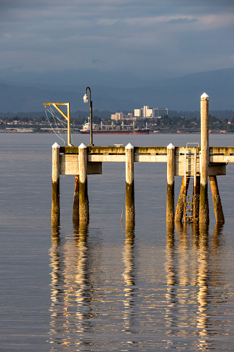 Late afternoon sun shines on Pier at Mukilteo Ferry Terminal. In background city of Everett WA.