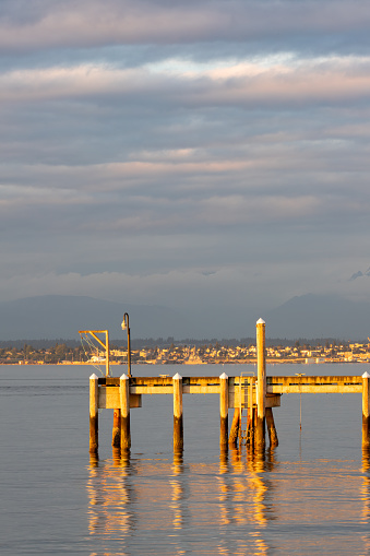 Late afternoon sun shines on Pier at Mukilteo Ferry Terminal. In background city of Everett WA.