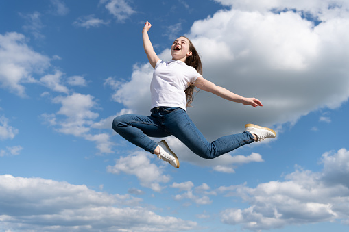 happy teen child jump on sky background.
