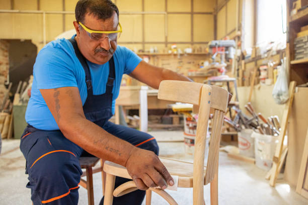 istock Indian carpenter working alone in his workshop. He is wearing safety glasses 1413288631