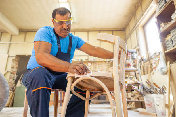 istock Indian carpenter working alone in his workshop. He is wearing safety glasses 1413289546