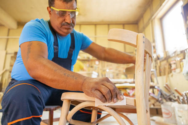 istock Indian carpenter working alone in his workshop. He is wearing safety glasses 1413289584