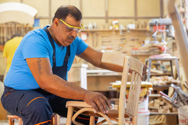 istock Indian carpenter working alone in his workshop. He is wearing safety glasses 1413289593