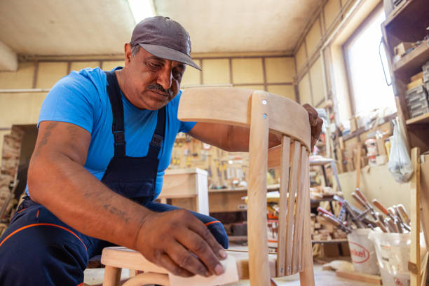 istock Indian carpenter working alone in his workshop in a squatting position 1413290067