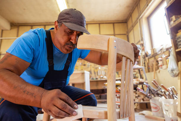 istock Indian carpenter working alone in his workshop in a squatting position 1413290110
