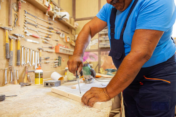 Indian carpenter making a wooden chair. Using a screwdriver.